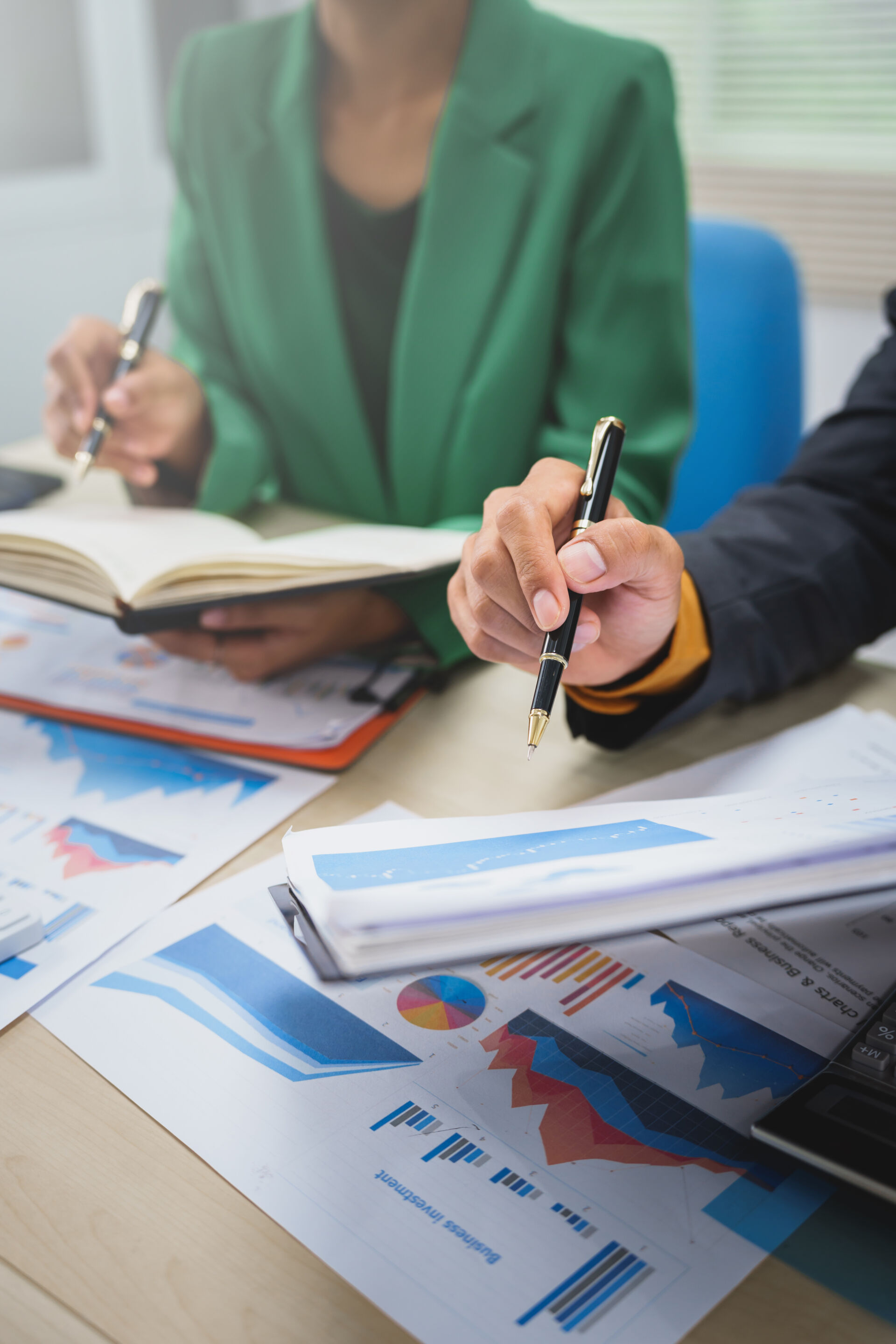 Asian business team in formal suits collaborates on financial charts, brainstorming company growth