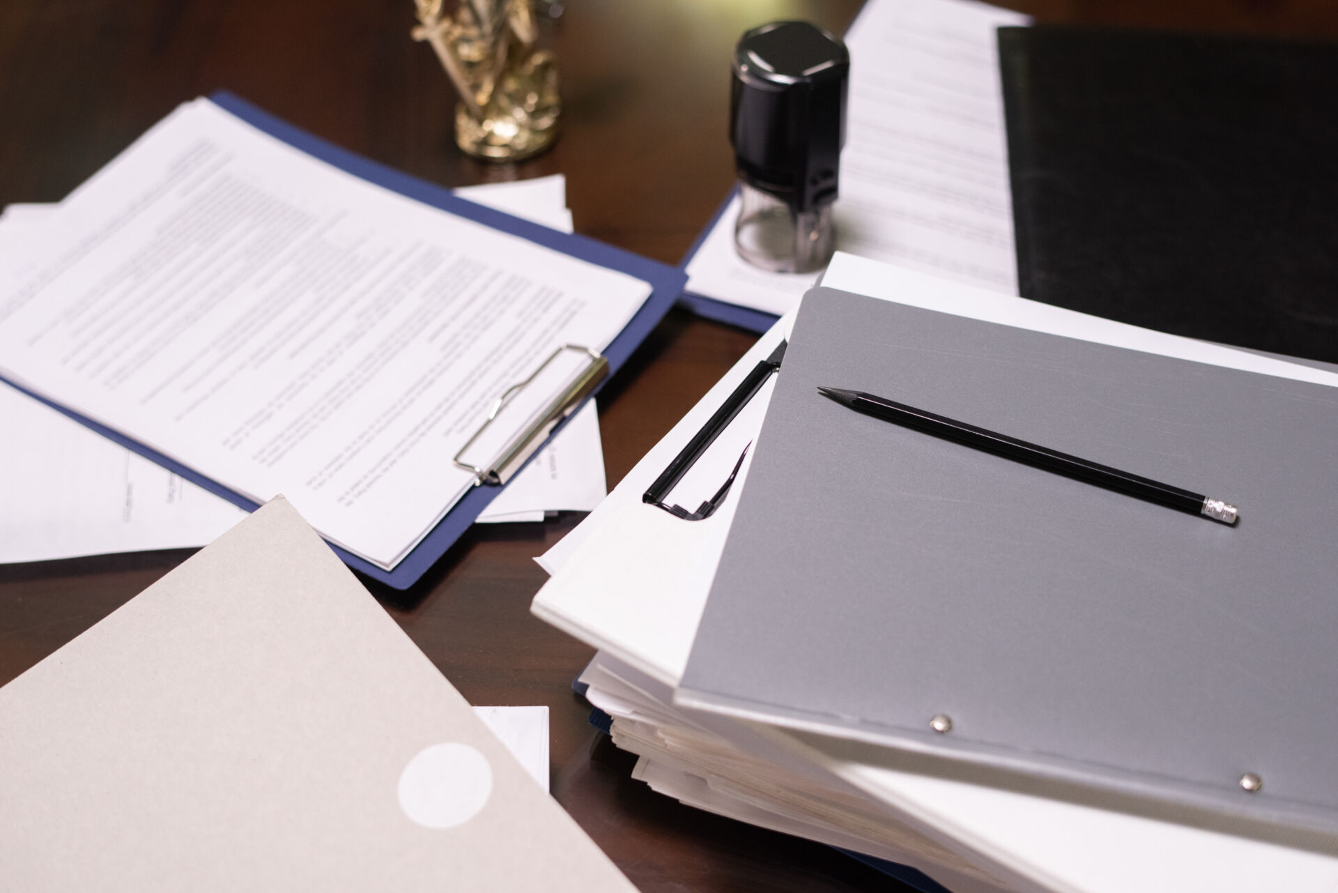 Part of table with stacks of juridical and business documents in folders and clipboards with pencil on top