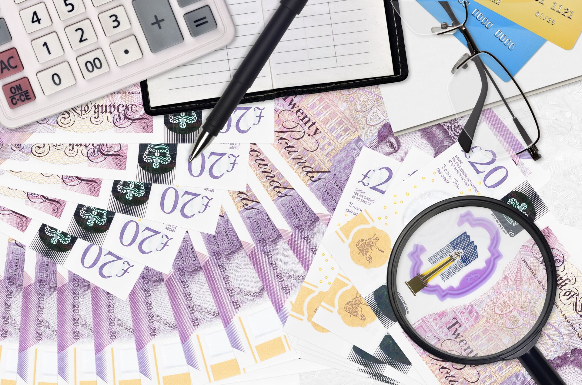 20 British pounds bills and calculator with glasses and pen. Tax payment season concept or investment solutions. Searching a job with high salary earnings